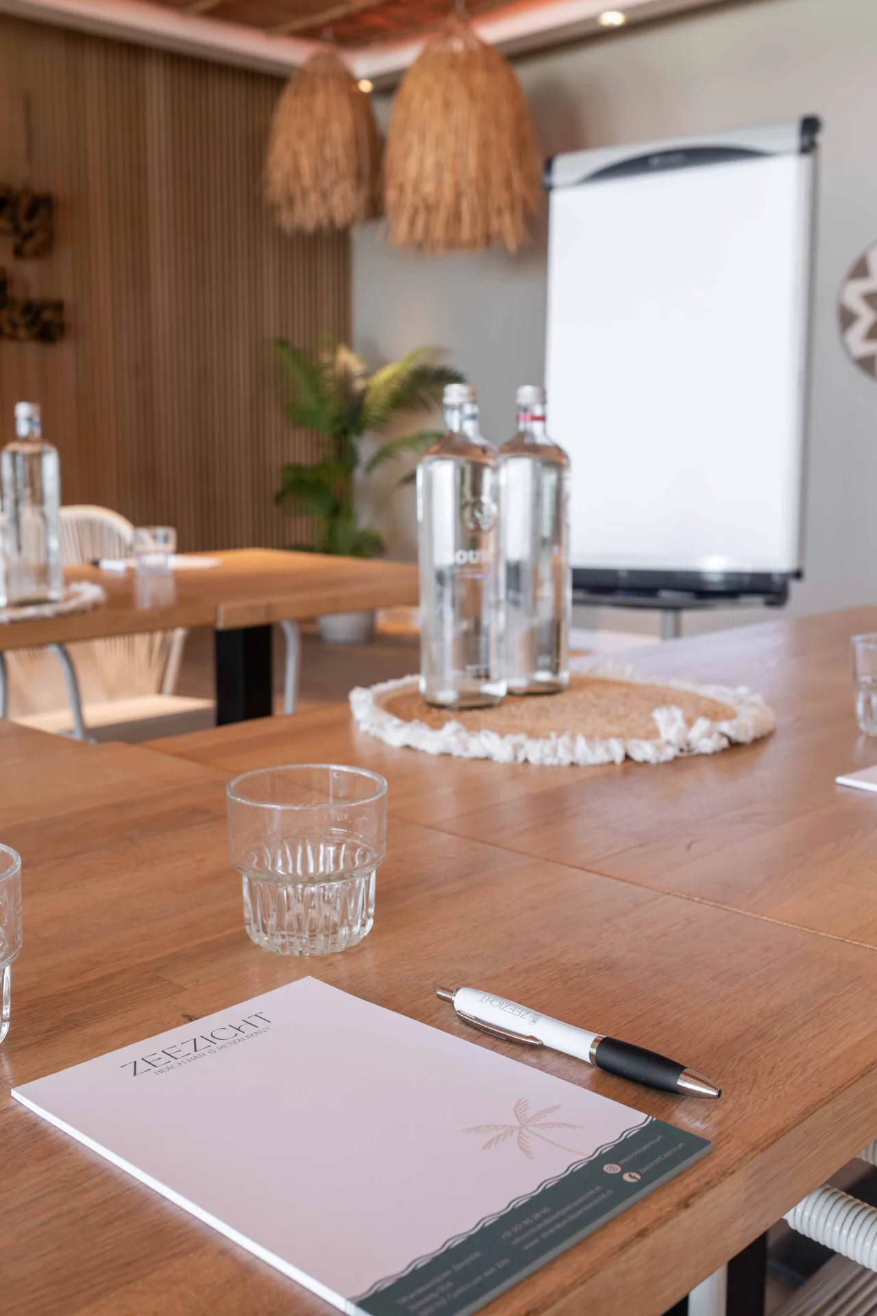Vergadertafel bij Zeezicht met notitieblok, pen, flessen water en een flipover op de achtergrond.